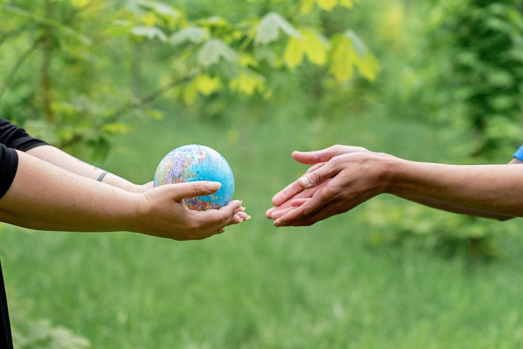 pexels-photo-8542538-8542538 Two hands exchanging a small globe symbolizing global unity and ecology awareness.